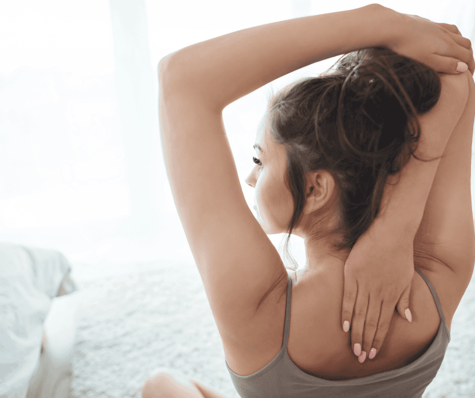 young woman stretching her arms overhead in a bright, airy bedroom — starting her morning with intention and mindfulness