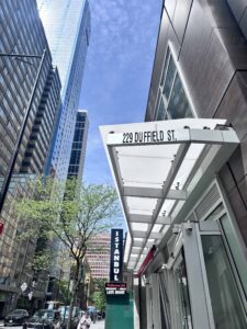 View of 229 Duffield Street in Downtown Brooklyn on a sunny day, with a clear blue sky, tall modern buildings,