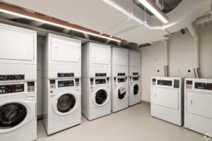 Bright, clean laundry room with multiple stacked washers and dryers, offering convenient on-site laundry access for residents.